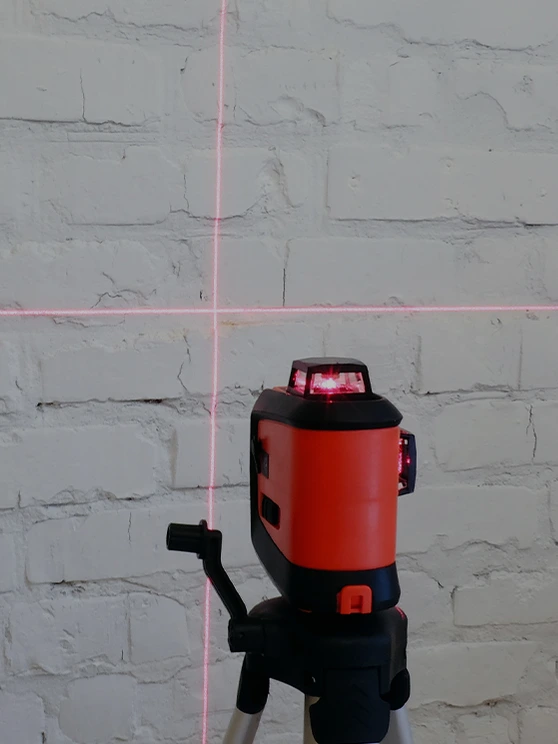 Lasermessgerät projiziert Messlinien auf eine Wand beim Aufmaß